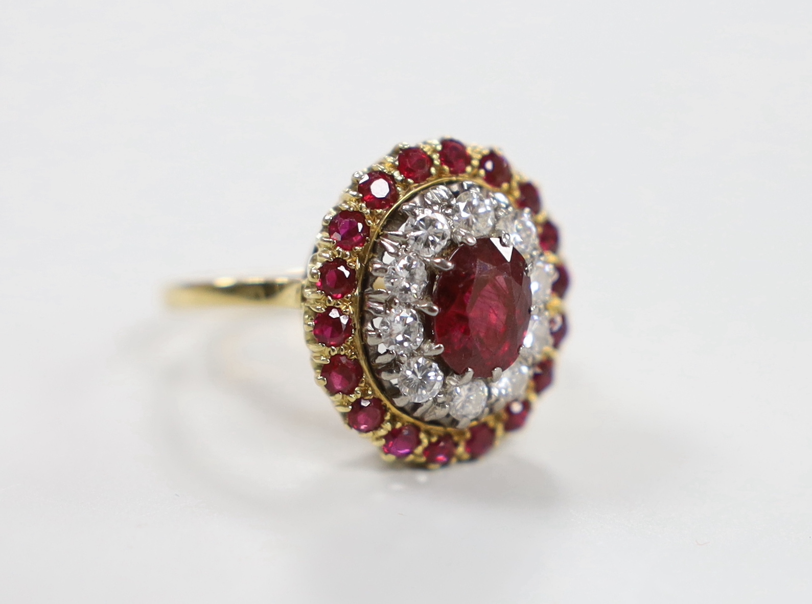 An 18ct, ruby and diamond cluster set oval cluster dress ring, size N/O, gross weight 6.3 grams.
